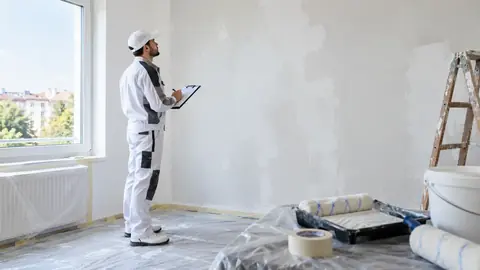 Peintre inspectant un mur préparé avec une feuille de contrôle